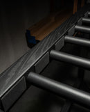 Blackout freestanding wooden surf board rack made from red oak, and painted in a flat-black finish showing the top of the rack. There are high quality foam dowels coming off the rack