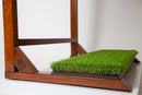 Finished Grassy surf rack base close up shot focused on the faux grass base where the surfboards rest. The rack is made of a high-gloss finished wood that is dark in color.