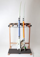 Front main photo of the Foamy freestanding surfboard rack meant to hold up to 5 boards. The rack is shown holding two high performance surfboards one with orange stripes, the other with blue. The rack has a durable black pad at the bottom for surfboard protection.