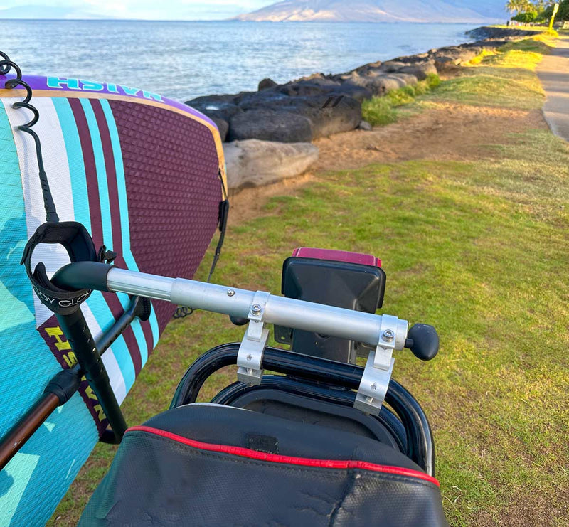 Close up of the rear mount point for the SUP moped rack. There is a teal stand up paddleboard in the rack while the moped sits on lush grass with the ocean in the background.
