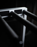 Marshmellow Surf Rack top right quadrant showing the flat white finish. The surf rack is in a dark room, but there is a beautiful white light cast on the surf board rack.