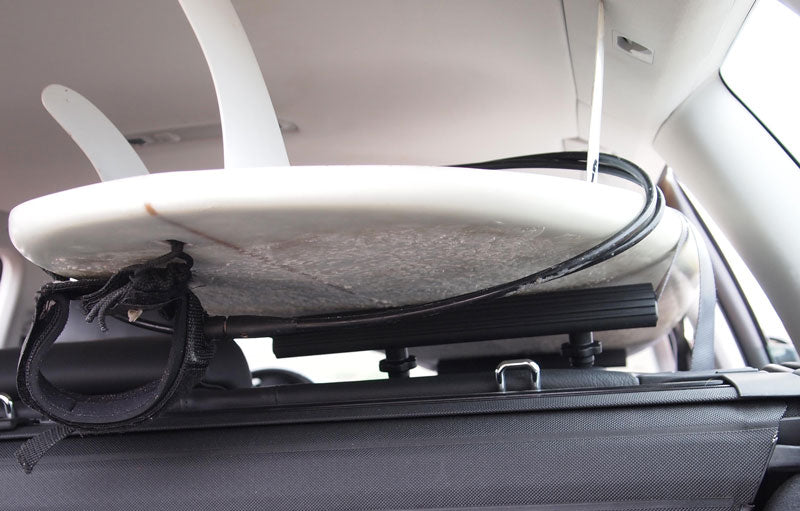 Close up of the SeatRack being used holding a white surfboard in the inside of a car.  