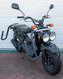 Dual-Mount Moped surf rack showing that it can also be mounted with it's dual-c clamp mounting system on a moped rack as well. The rack is mounted on a black Honda Ruckus