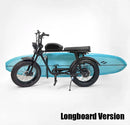 Black e-bike shown holding a blue longboard using the e-bike longboard racks. Black text at the bottom right of the image reads "Longboard Version"