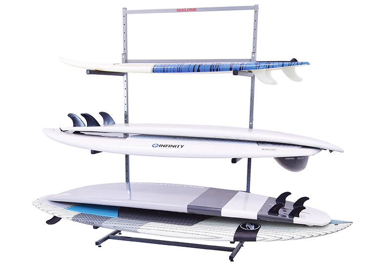 Metal Free-Standing Board Rack shown holding several Stand Up Paddle Boards and a surfboard. The rack is grey metal and has several levels that hold the watercraft in the horizontal position. 