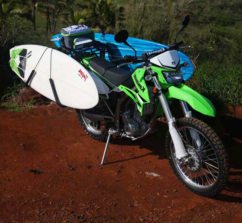 Single Mount Motorcycle & Moped Surfboard rack shown mounted to a Kawasaki dirt bike.  The bike actually has two surfboard racks mounted, one on each side, with a surfboard in each rack. 
