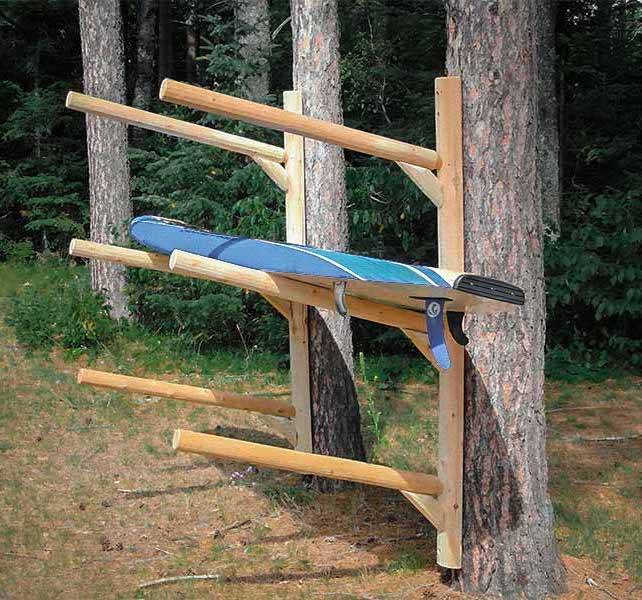 3 board SUP, Kayak, or Canoe wall mountable log rack mounted to a tree. The rack is holding a single SUP in the middle level.  