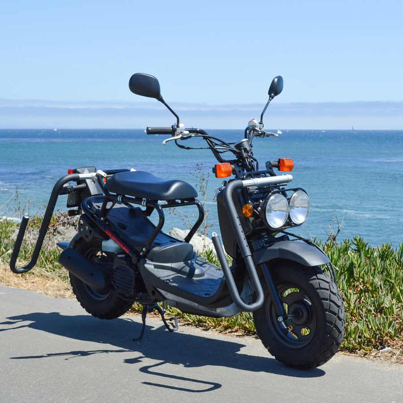 Honda Ruckus Moped parked at the beach using the dual-mount surfboard rack having no board on the rack