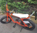 Super 73 orange and white e-bike with the longboard rack mounted to the front and rear of the bike.
