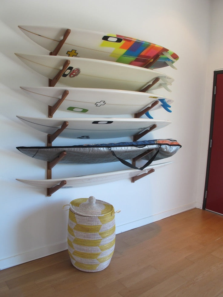 Wood Multi | Surf Rack for 1-4 boards storing multiple boards shown holding several shortboard surfboards in a bedroom.  The rack is mounted to a white wall, and there are wooden floors. 