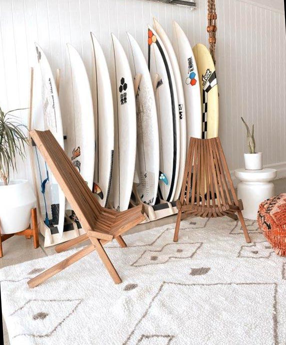 Surfboard Rack shown inside a comfortable home displaying 9 surfboards.  There's also an area to hangout in with chairs and other furniture in the foreground. 