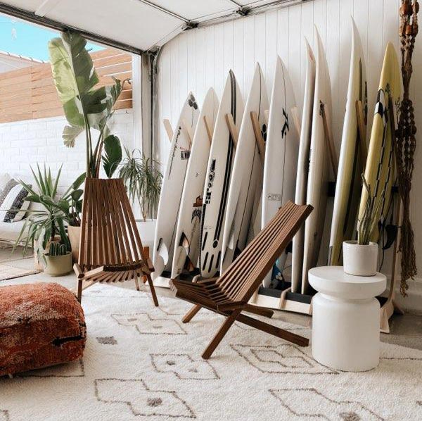 Multiple surfboard freestanding rack storing several surfboards and furniture.   Looks like a very relaxing environment to relax and hangout. 