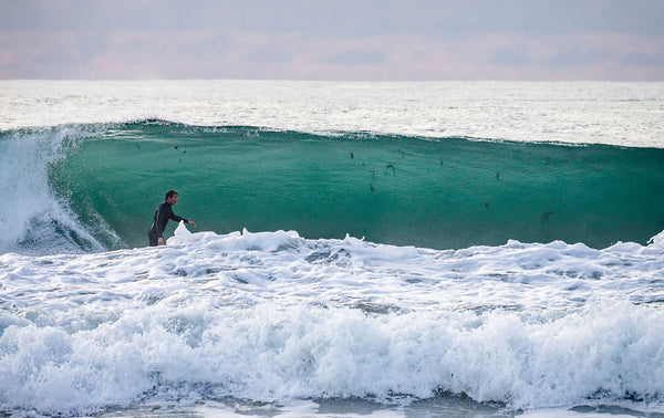 Surfer pulling into an over head wave that is clear and green.  Looks to be setting up to pull into the barrel.