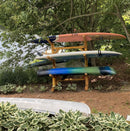 4 Kayak or SUP Log rack shown near a lake holding multiple watercraft with some green plants in the foreground and background.  