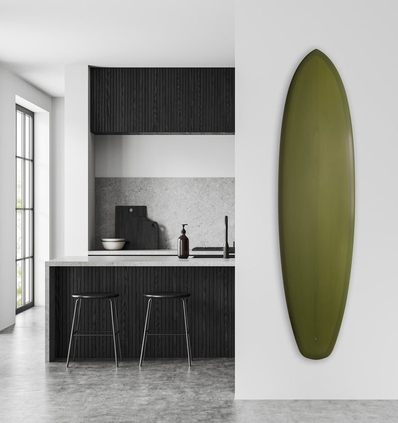 Acrylic vertical surfboard wall mount holding a Green surfboard in a kitchen a high end kitchen with black trimming and wood.  There is a marble floor , and the wall is white. 
