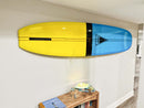 Yellow and blue longboard mounted on a wall in a room using a clear acrylic surfboard wall rack.