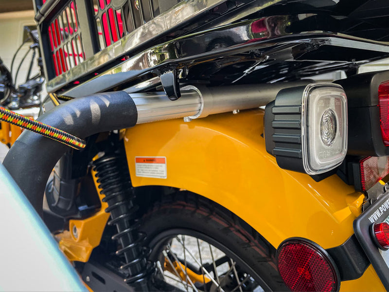 Close up view of the moped surfboard rack's rear attachment point on a Honda Moped. The surf rack is mounted directly below the moped's rear luggage rack.