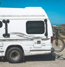 Seasucker rack shown d mounted directly to the side of an RV recreational vehicle parked on the beach.  There is a bike mounted on the back of the vehicle. 