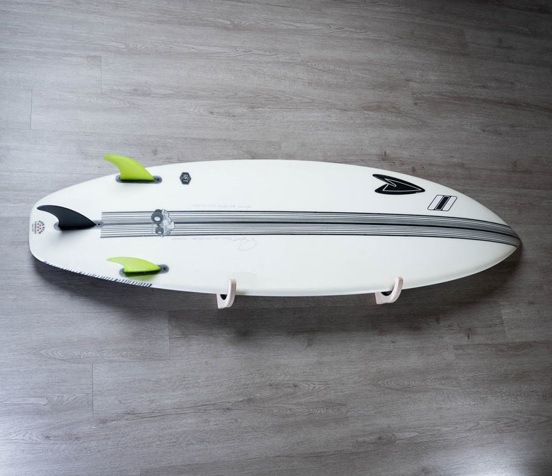 Wood single surfboard wall rack holding a white shortboard with green fins on a grey wooden wall.  The board is stored in the horizontal position.