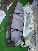 A black and grey surfboard travel bag is shown open.  The underside has a silver reflective lining.  There are drawstrings on the inside of the bag to secure the boards. 