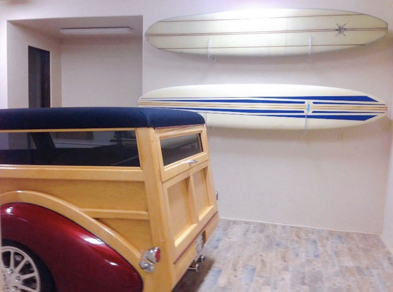 2 longboards held in a high-end garage mounted above an old woody vehicle using acrylic longboard racks