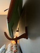 Wooden surfboard rack with a surfboard mounted on a wall.