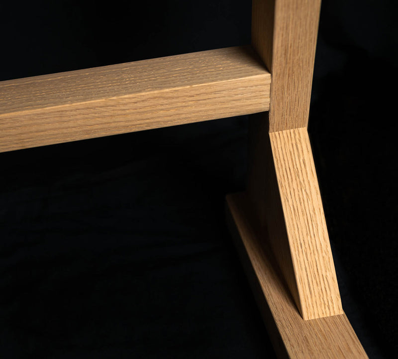 Detail of red-oak hand made rack for surfboards bottom corner and cross bar.  Picture shows dramatic lighting showing off the wood's quality grain. 
