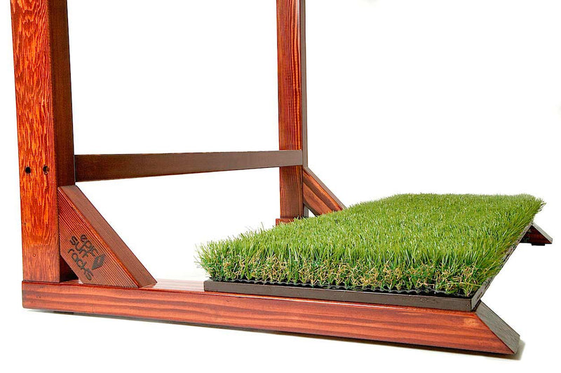 Close up image of the Finished Grassy Surf Rack's grass turf base. The wood is a dark brown.  The image is on a white background. 