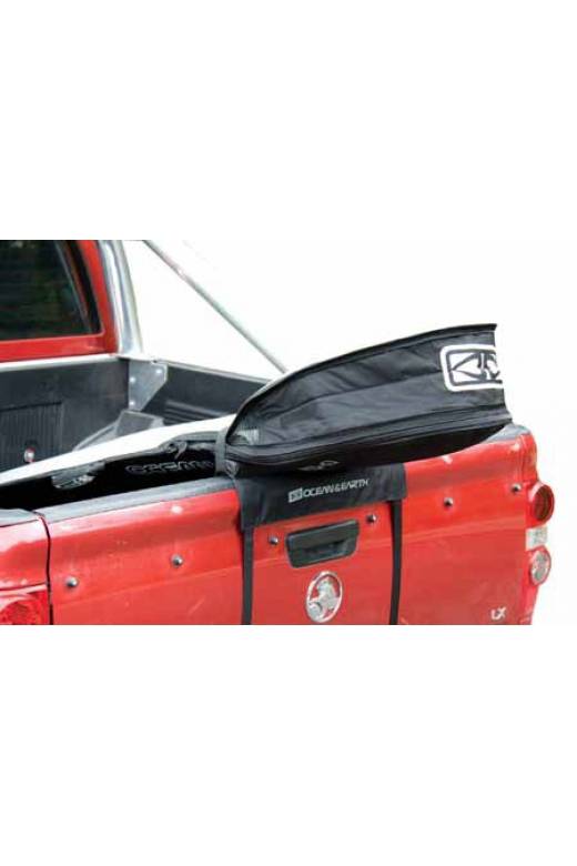 Tailgate Rax shown mounted to the back of a red pickup truck's tailgate.  The rack has a surfboard mounted in a board bag. 