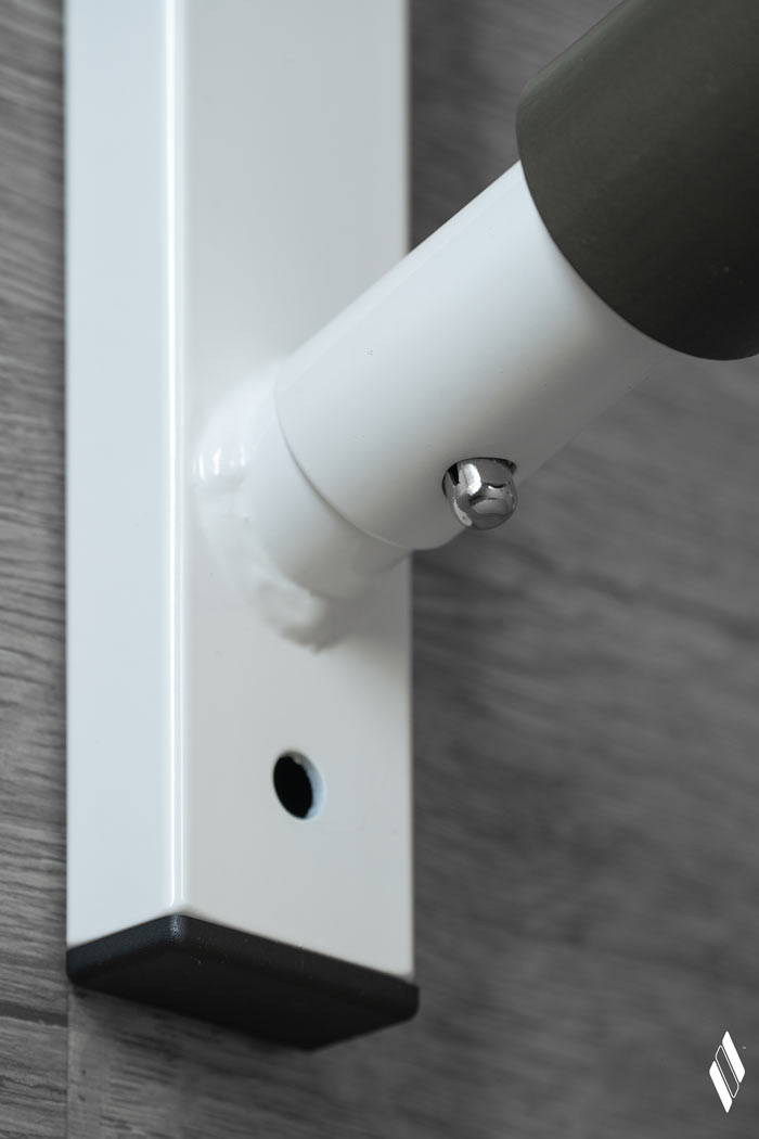 Close up of the quick-release push pin mechanism that allows the dowels to be easily uninstalled or reversed to have an angled-up board/kayak position.  The rack is covered in a high-gloss white protective paint and has black finishing caps with green foam for watercraft protection. 