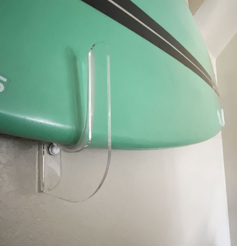 Acrylic flush mount shown holding a green surfboard close to the wall. The surfboard being held is green with a black stripe. 