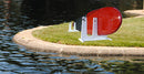SUP & Surfboard Rack for Docks and Piers shown on a plot of grass next to a lake. The white SUP rack is holding a single red stand up paddle board rack.