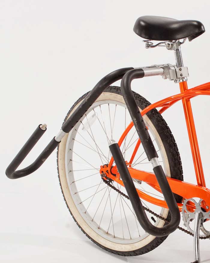 Close up image of the Surfboard Bike Rack | Single-Mount.  The image focuses on how the rack is attached to the vertical seat-post of a bicycle.  There are two arms that come off the rack to hold a surfboard. 
