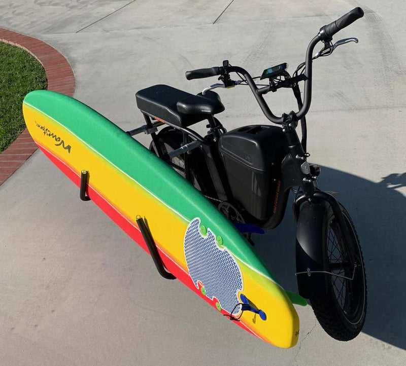 black e-bicycle using dual-mount rack holding rasta colored wavestorm foamy soft top surfboard